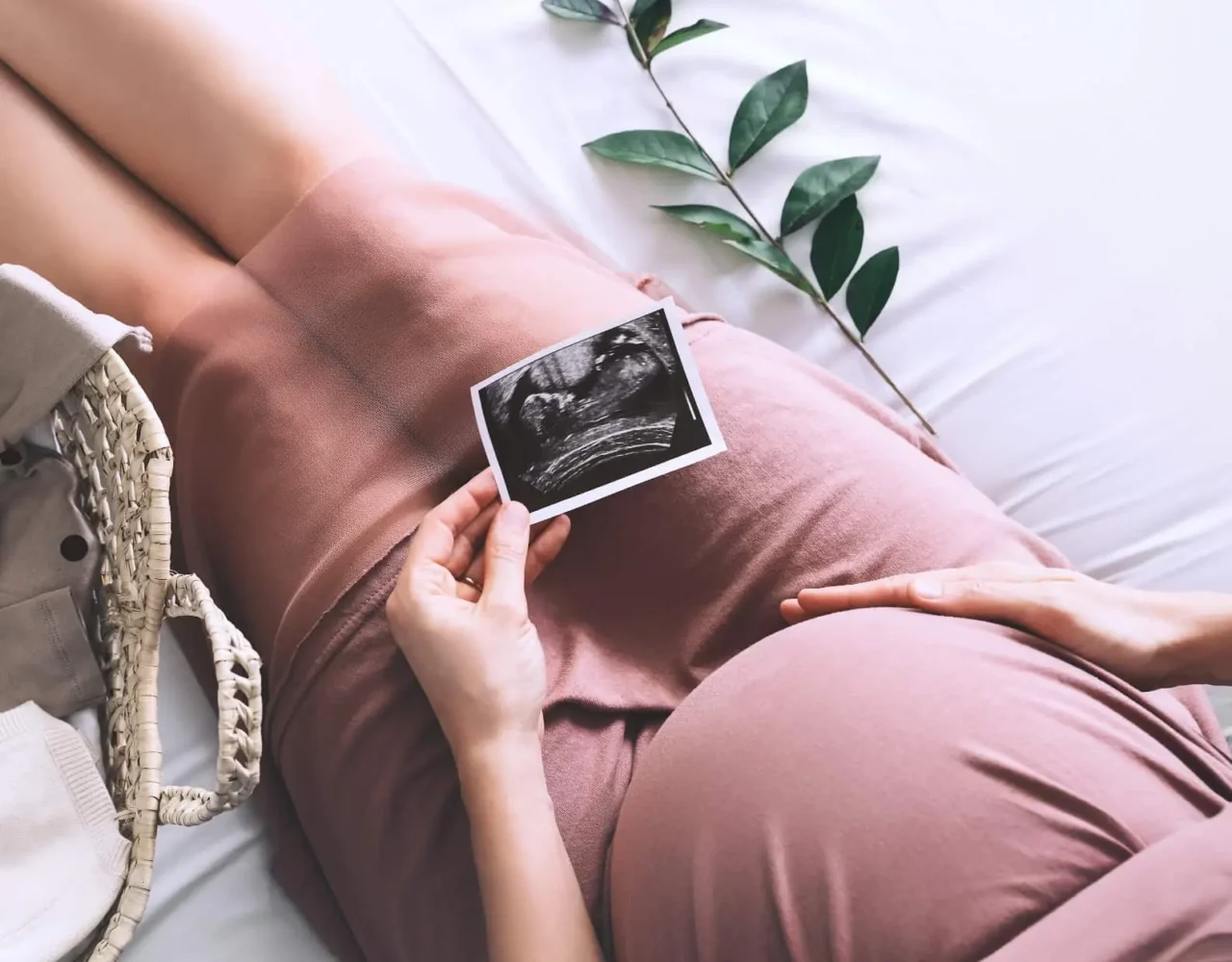 pregnant woman looking at ultrasound photo of baby