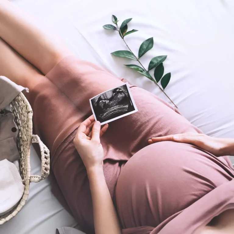 pregnant woman looking at ultrasound photo of baby